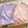 Minh họa áo lớp pastel hồng và tím với hình mây và ngôi sao